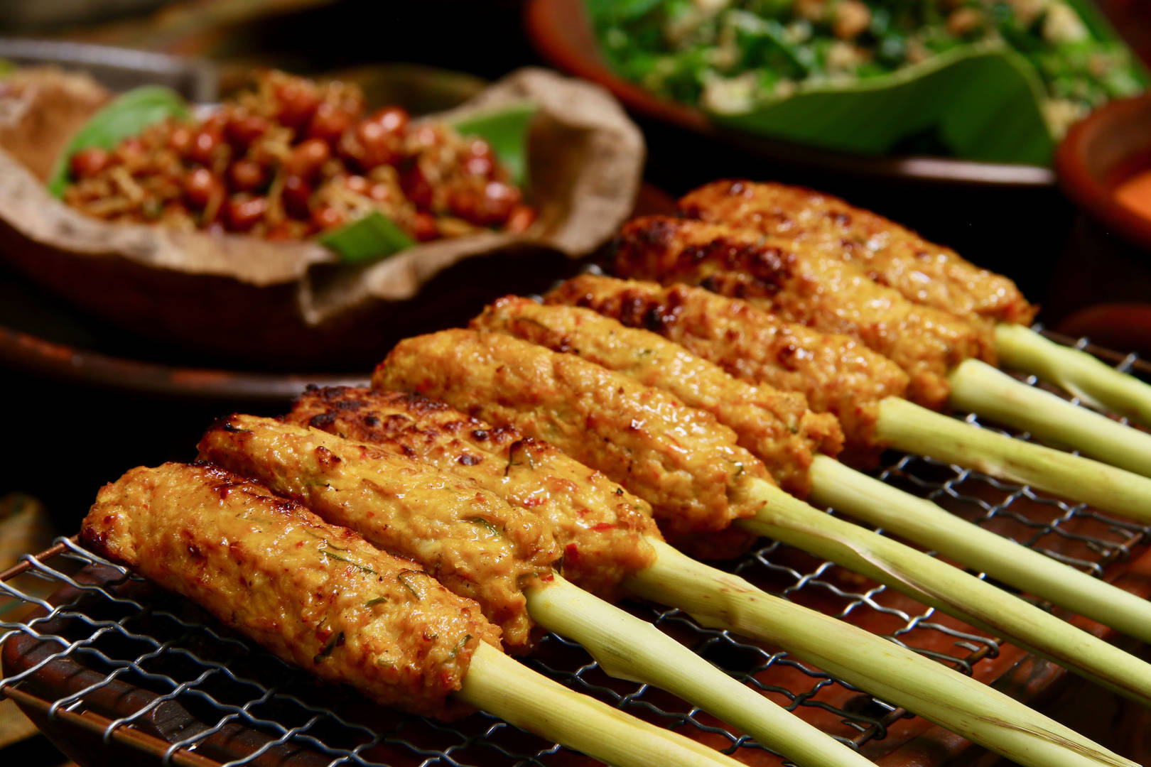 Skewers of Satay Lilit, a Balinese dish, grilling on a barbecue