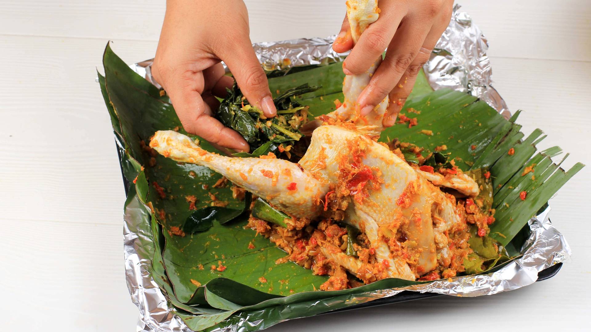 The cooking process for making Ayam Betutu, a Balinese spiced chicken dish