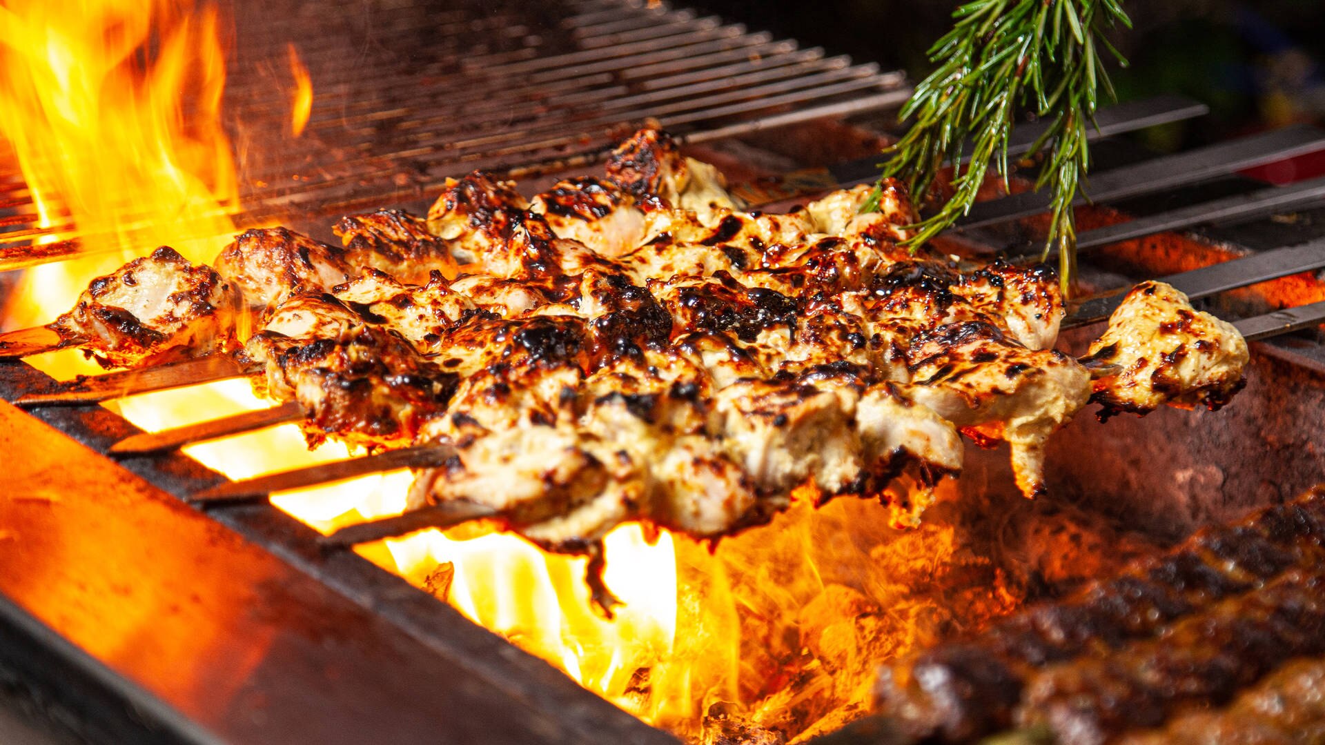 Image of kebabs cooking on a flame grill at the Friday Backyard BBQ at Jumeirah Creekside Hotel