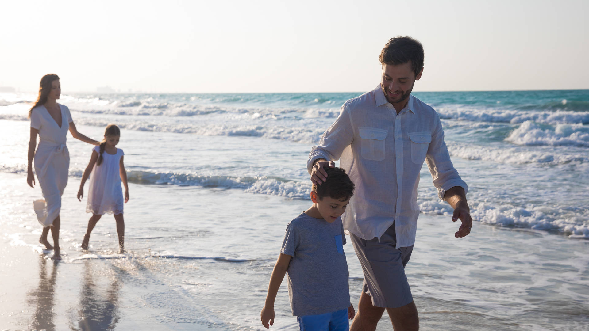 Family walking along the shore at Jumeirah Saadiyat Island Resort