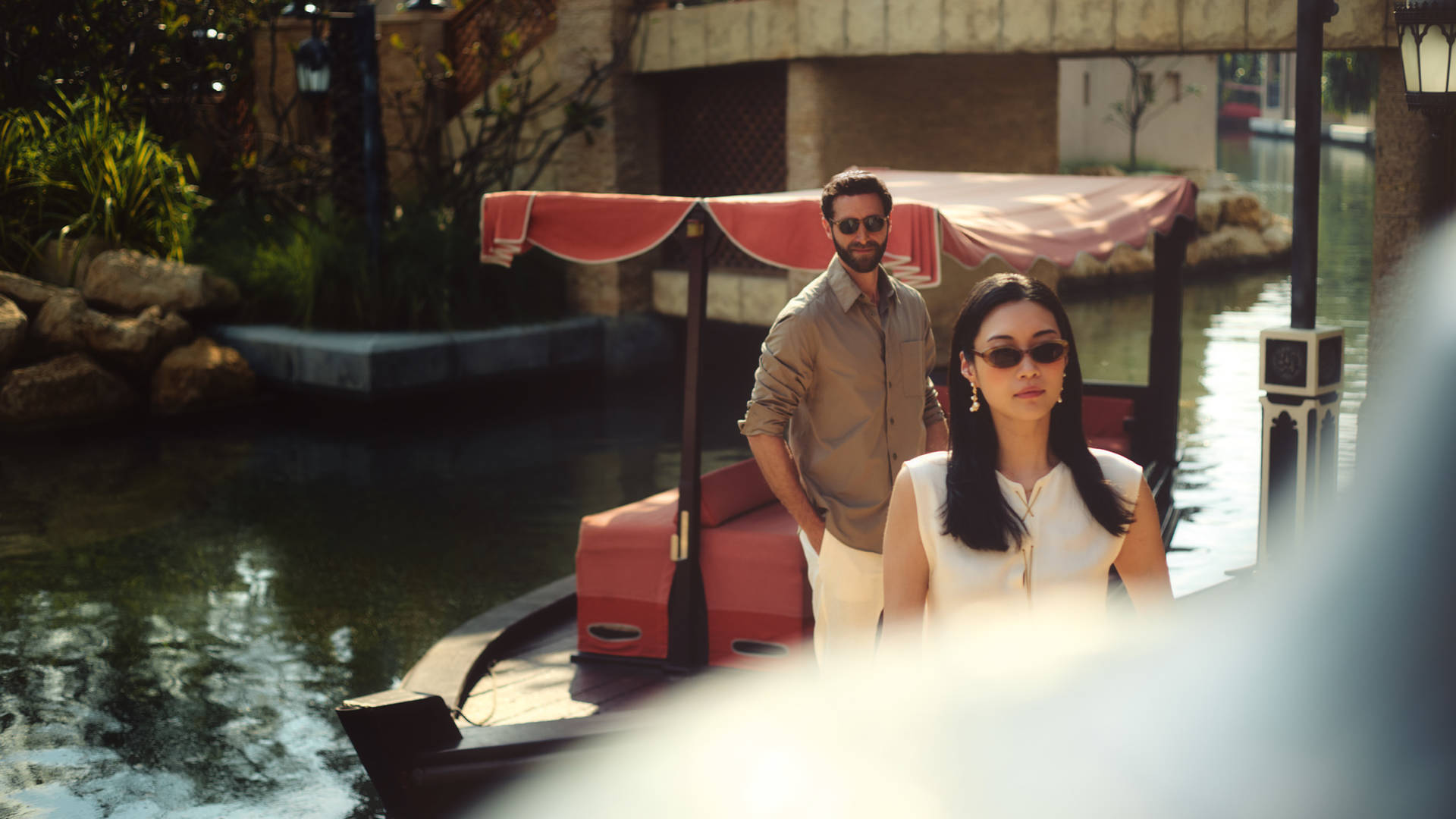 Image of a couple standing next to a traditional Abra boat, alongside the waterways of Madinat Jumeirah
