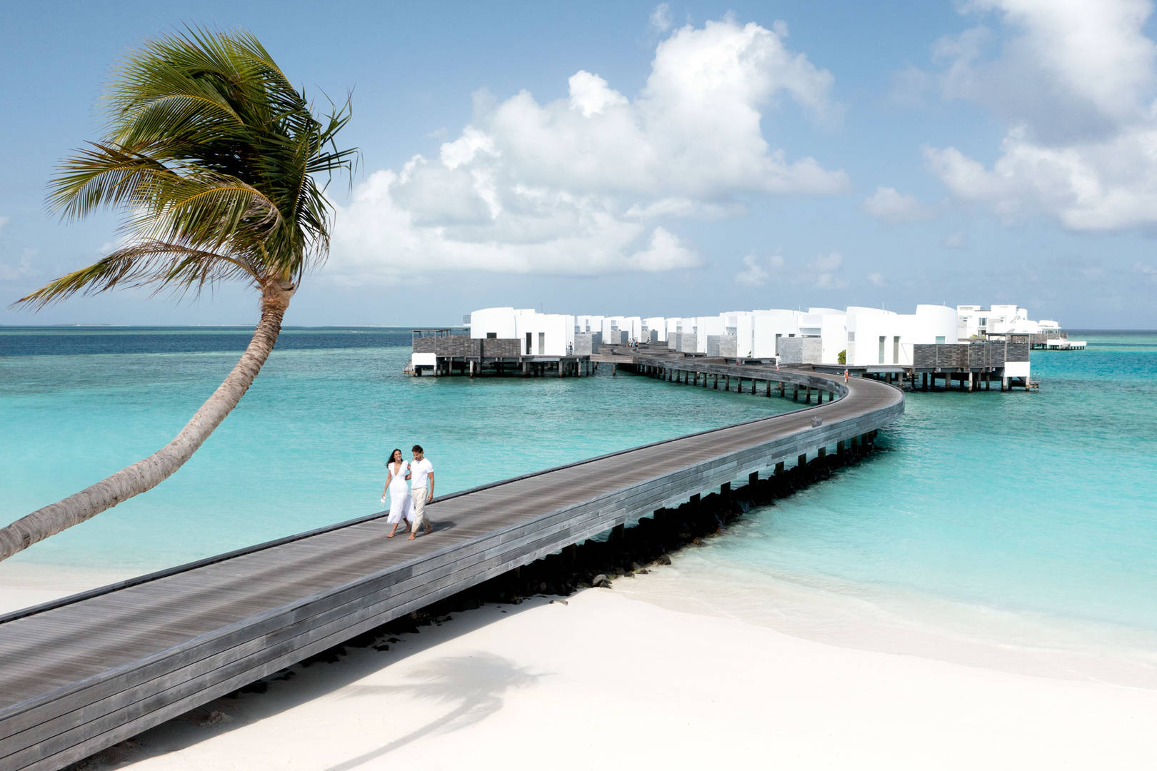 Couple walking along private beach at Jumeirah Maldives