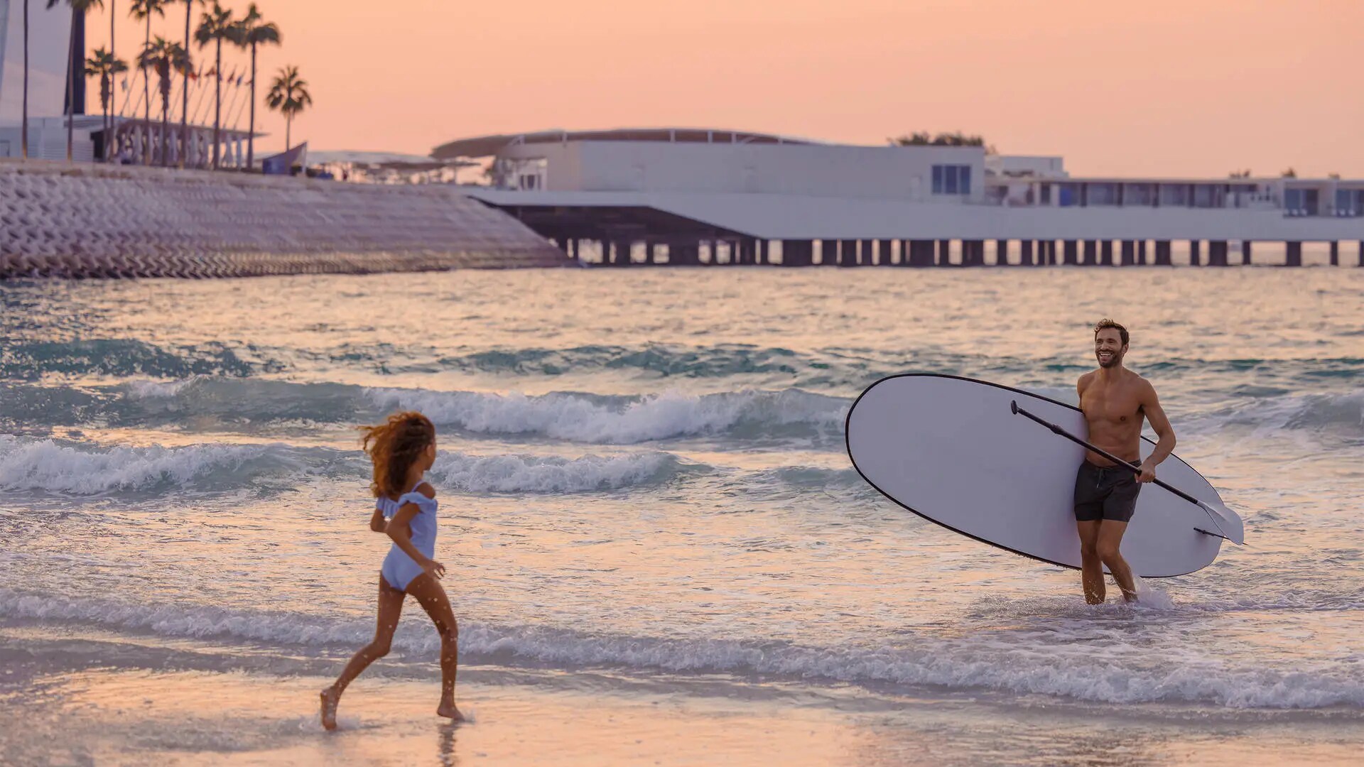 Daughter running along the beach front to meet her father at Jumeirah Beach Hotel