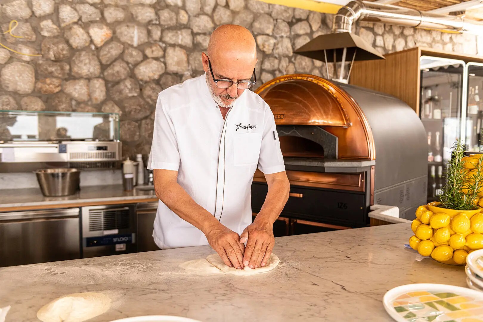 An image of Franco Pepe in the kitchen at a-Ma-Re Capri, preparing the dough of one of his pizzas