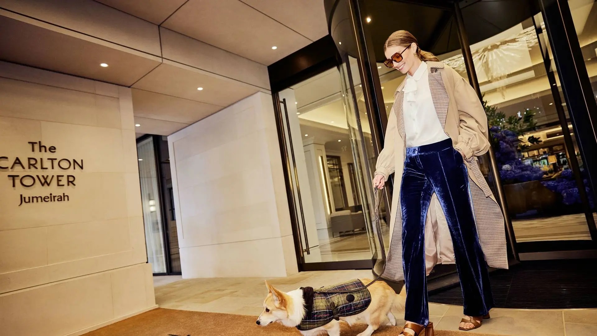 A woman and her dog exit Jumeirah Carlton Tower