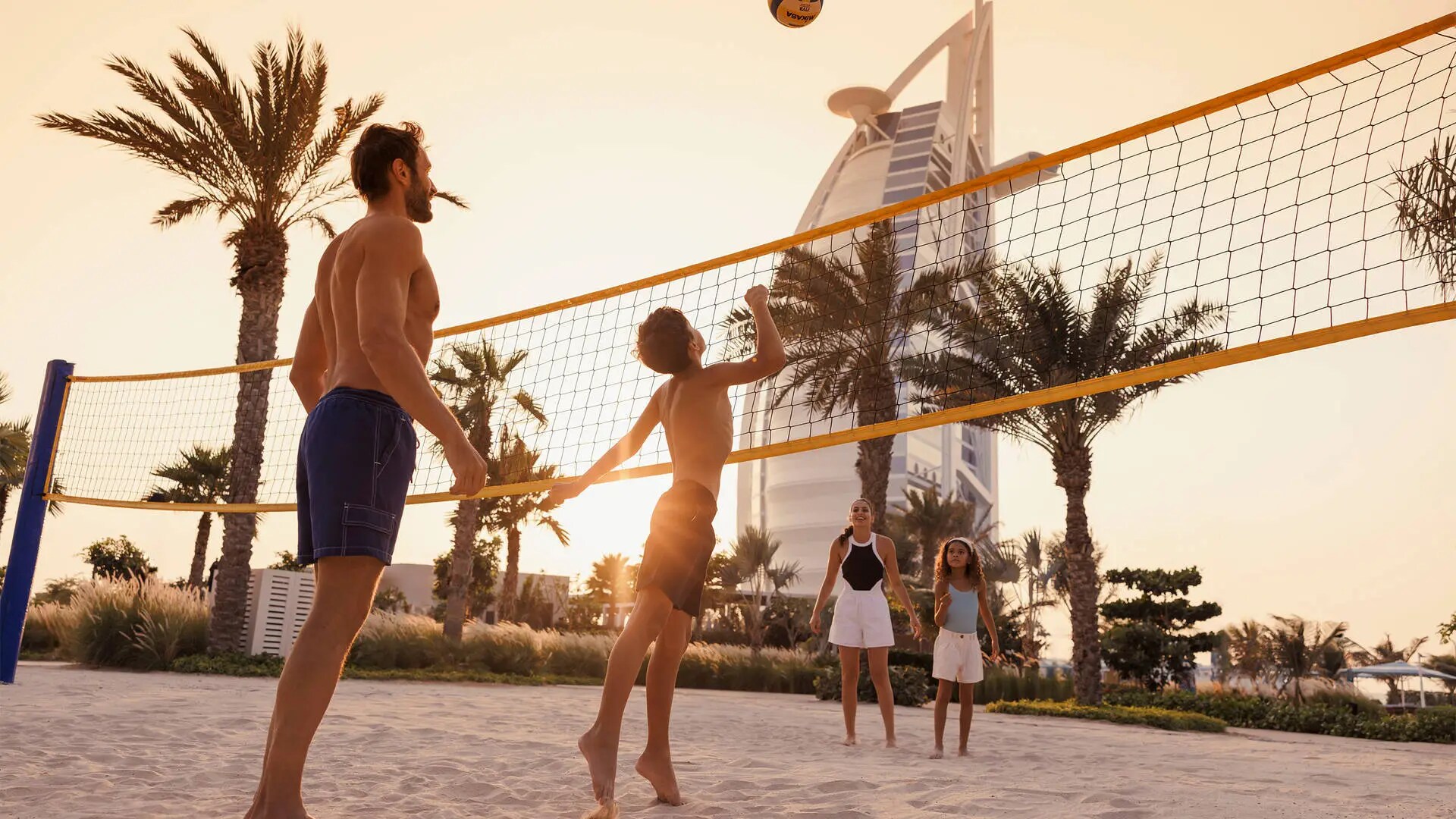 Family of four playing volleyball in front of the Burj al Arab at Jumeirah Beach Hotel
